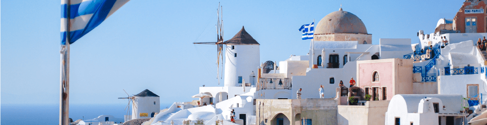 藍天與希臘岸邊的建築,飄揚著希臘國旗。