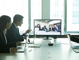 三位上班族在全白會議室進行視訊會議的照片