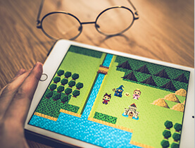 使用平板玩遊戲,旁邊木桌上放置圓細框眼鏡的照片