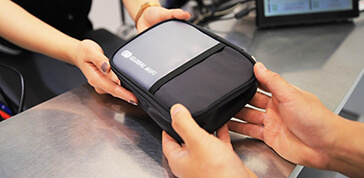 櫃台人員將WiFi包包遞給客人