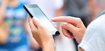 左手拿智慧型手機並用右手食指操作的特寫