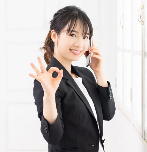 左手接聽手機右手勢比OK,穿著西裝綁馬尾的女性